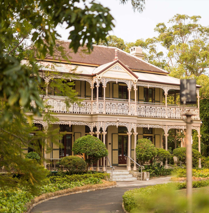 Victorian-era Architecture at Boronia House the new home of All Saint Clinic in Mosman, Sydney Australia. Featuring intricate white lace detailing on the facade, surrounded by greenery.