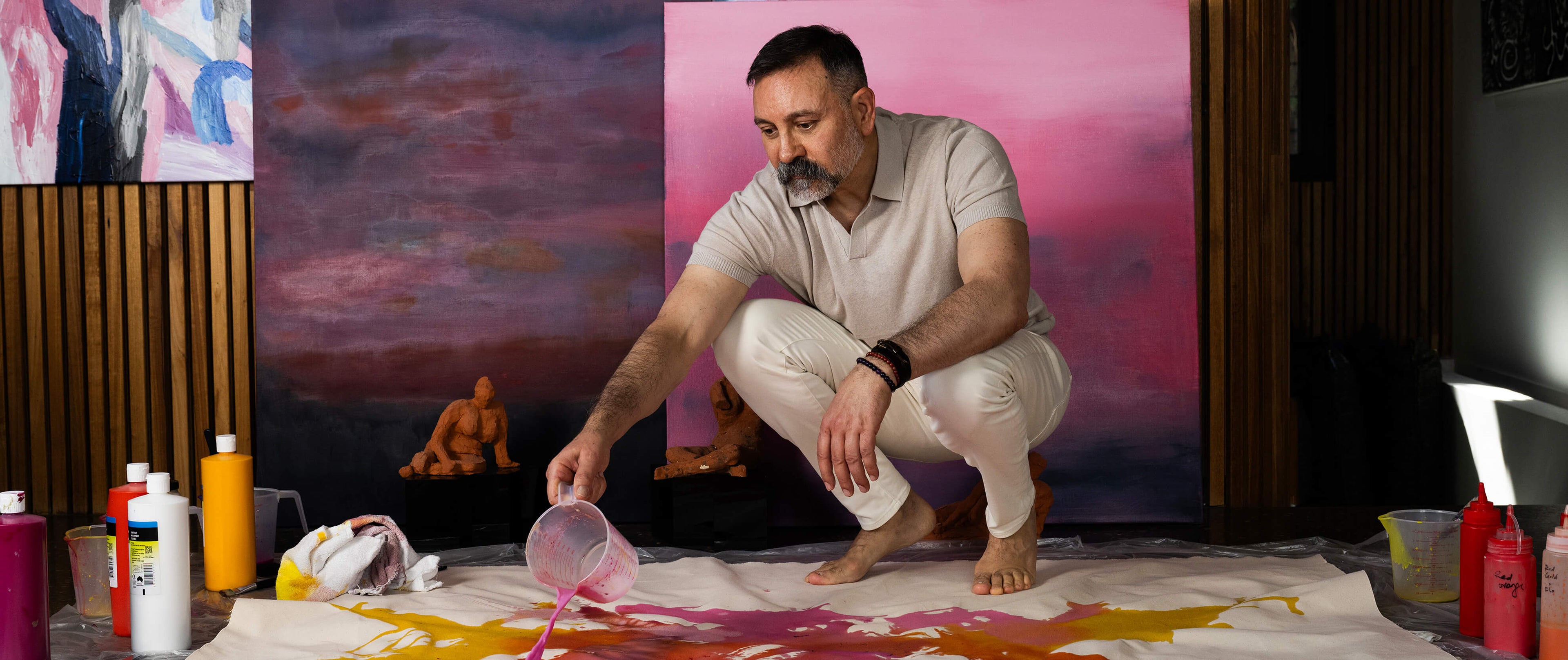 Doctor Joseph Hkeik in a studio with art supplies and colourful paintings in the background. A feature in the financial Review.