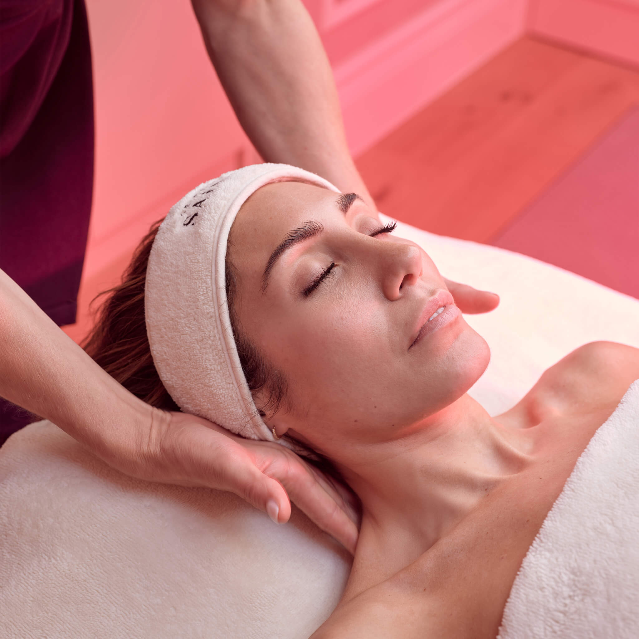 Woman receiving a red carpet facial by our head dermal therapist at the Le Petit Saint - a Medi Spa clinic. The room with radiating from the red light therapy. 