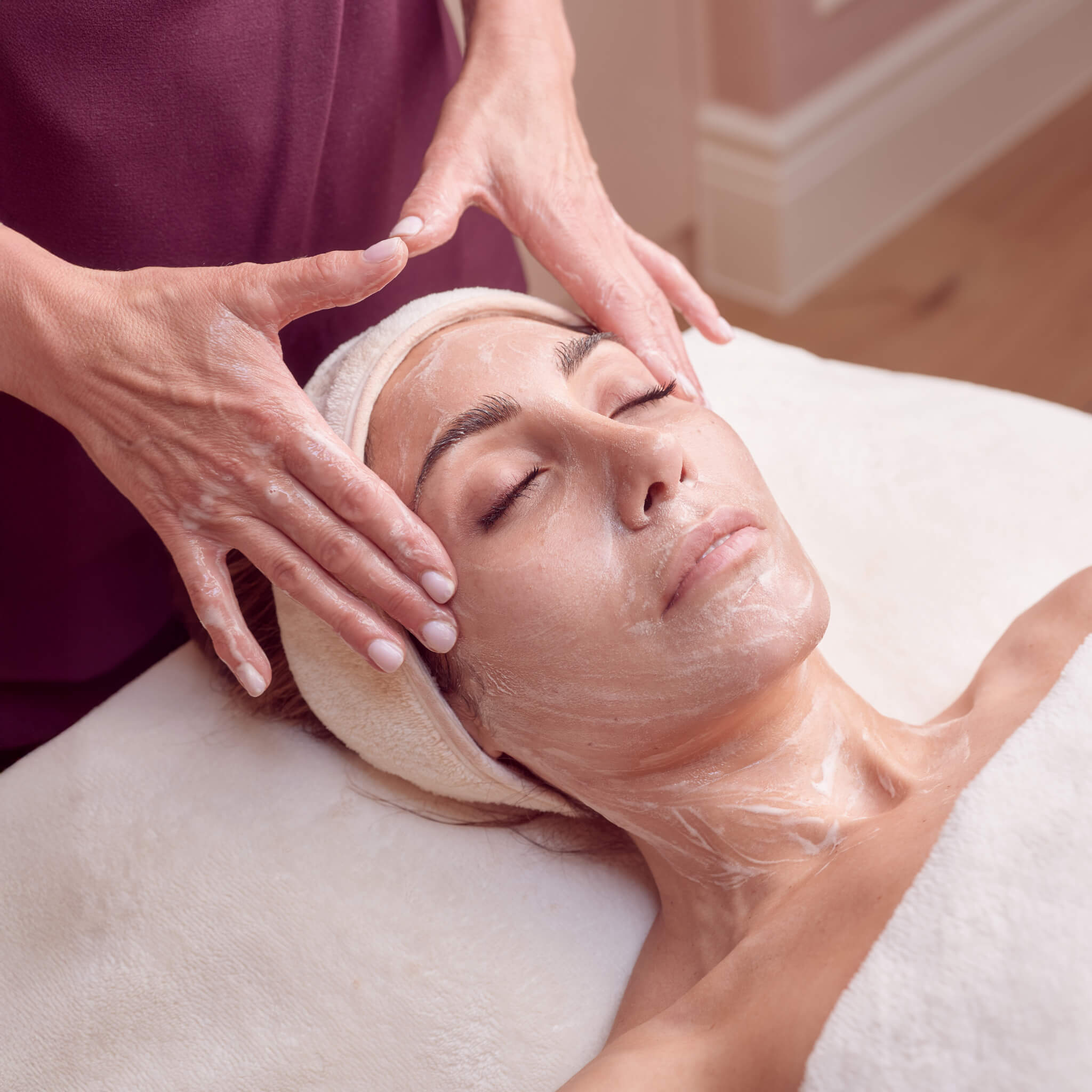 Woman receiving a facial in our Executive treatment room with a foaming enzyme mask on her face.  